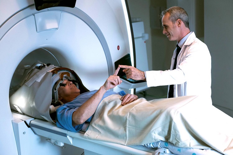 Patient in MRI machine and doctor touching fingers while conducting physiological test