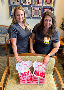 Two nurses pose with pink Mary Kay boxes