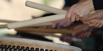 Hands hold drum sticks, drumming.