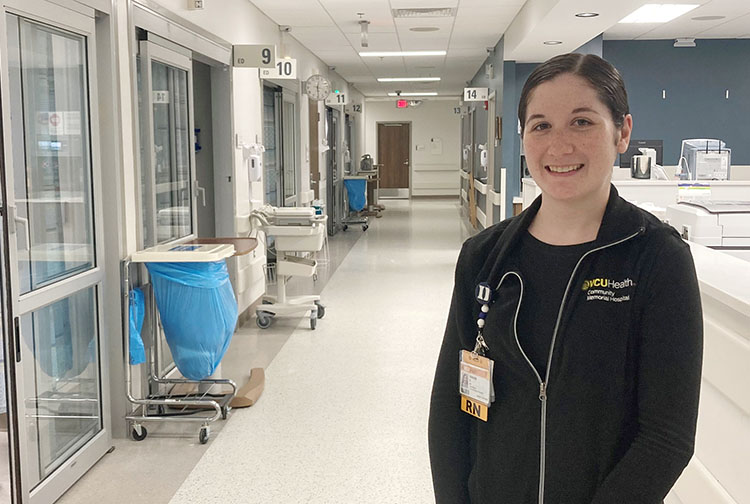 A nurse stands in an emergency room hallway.