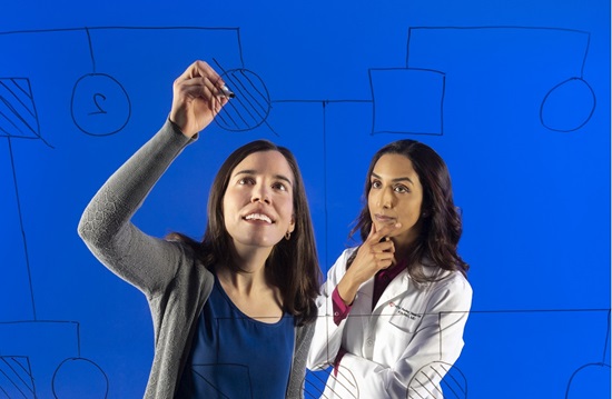 Woman drawing a diagram on a board and female doctor watching with her hand on her chin
