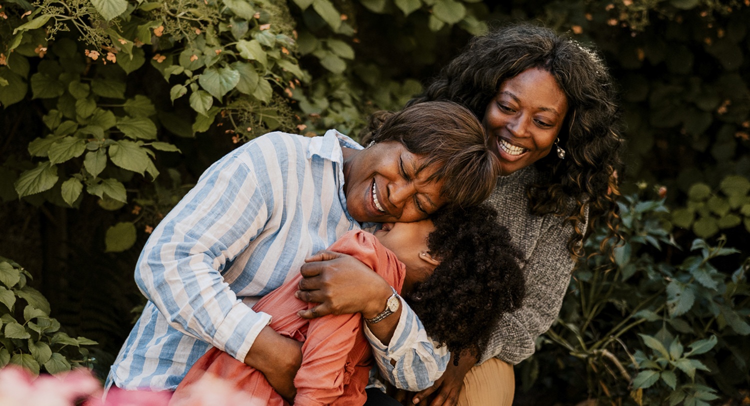 A family of three hugging and smiling.