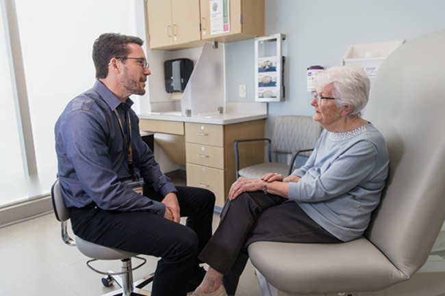 A doctor and patient sit together in an exam room.