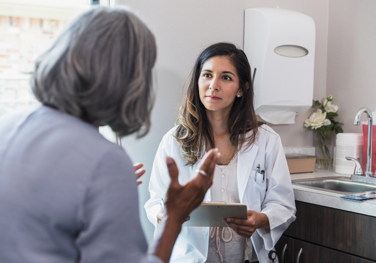 A provider is looking at a patient in a doctor’s office setting.
