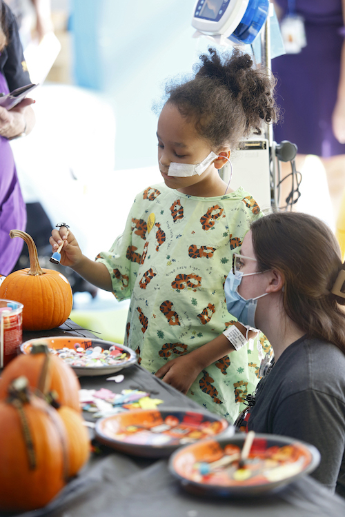 A little girl paints a pumpkin.