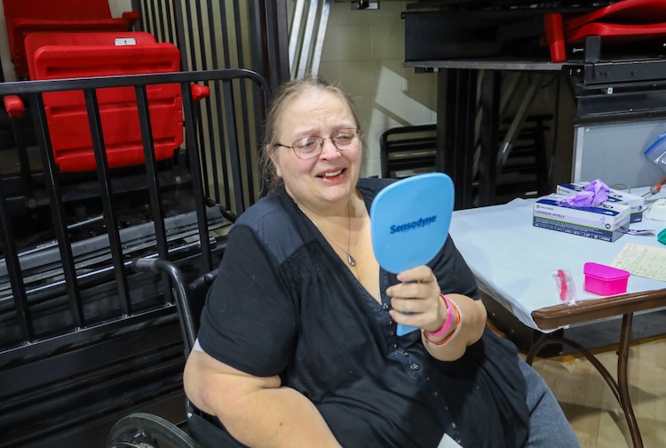 Patient looks at herself in a handheld mirror and smiles