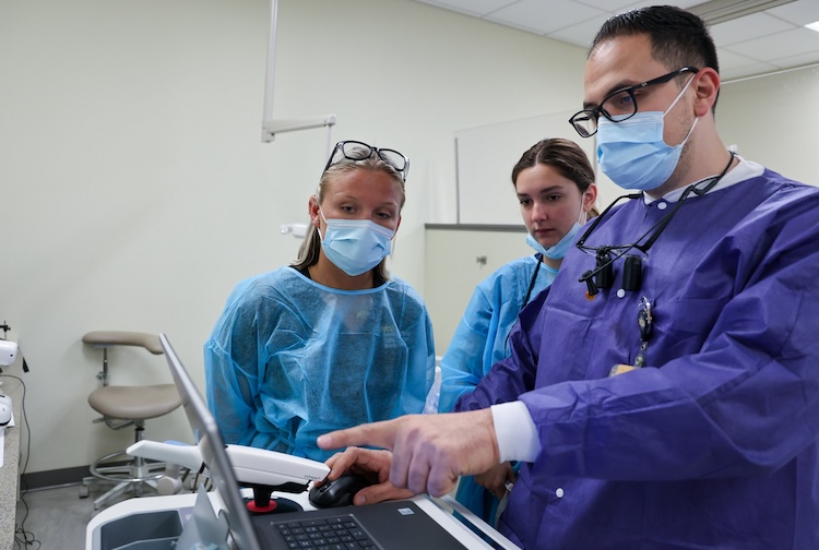 Dentist points to images on a computer screen