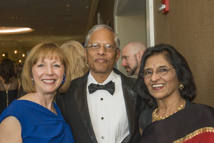 man standing in the middle of two women in formal attire