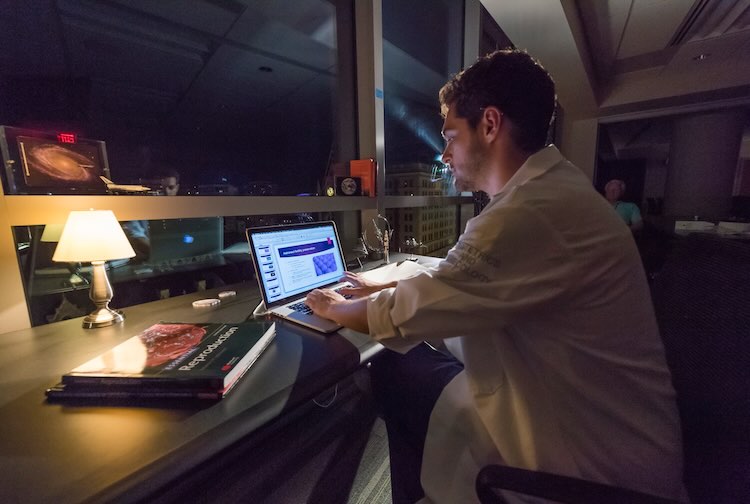 Students at a desk looking at researching on a laptop