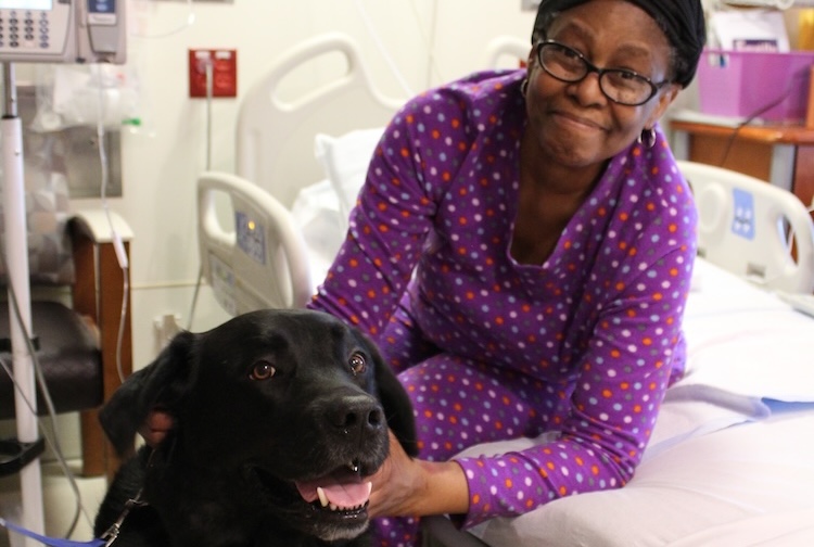 Patient sitting on side of bed petting dog