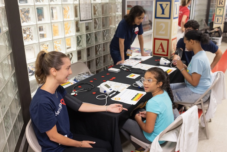 Table is set up in a hallway. Pauley Heart Center team members are speaking with students.