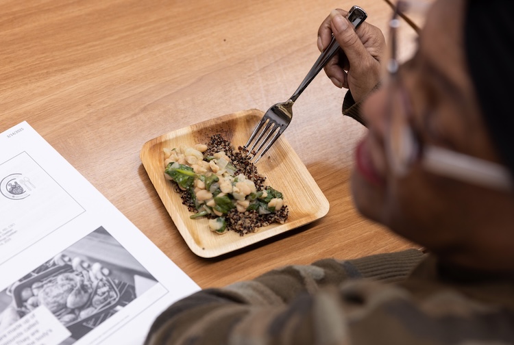 A female cancer patient is eating a well balanced meal prepared by members of the Food is Medicine program, as part of a group nutrition and cooking class.