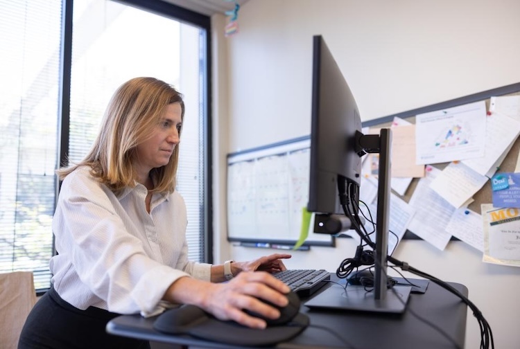 Woman sits at desk working on computer
