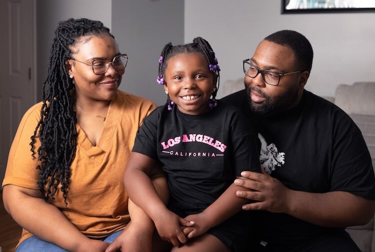 Kevin and his family sit together on a couch smiling