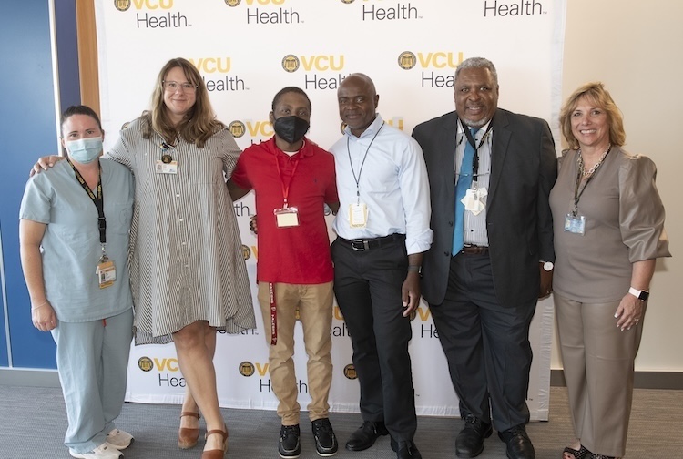 A group of VCU Health providers stand with patient Walter Davis in the middle.