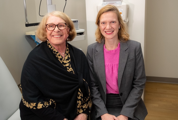Two women sitting next to each other smiling. One is a patient participating in a study, and the other is the doctor. 