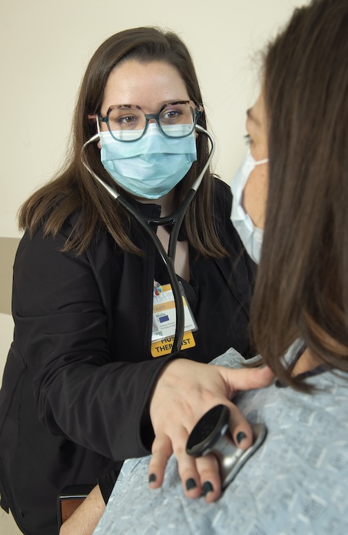 Woman listens to another woman's heartbeat through a stethoscope.