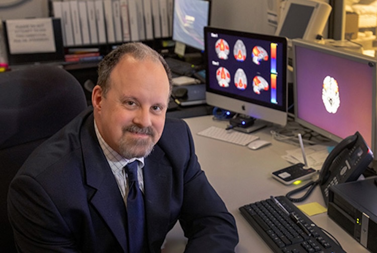 Man sits at desk wearing a suit