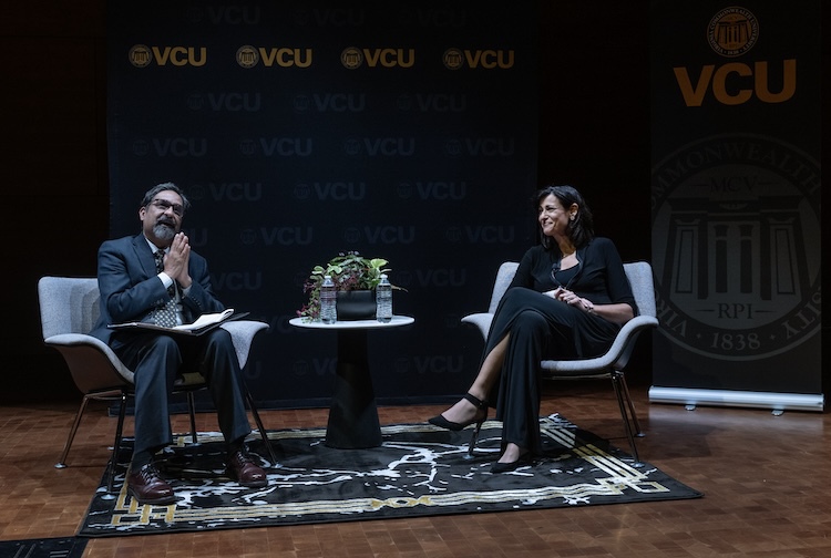 Two people sitting on chairs on a stage