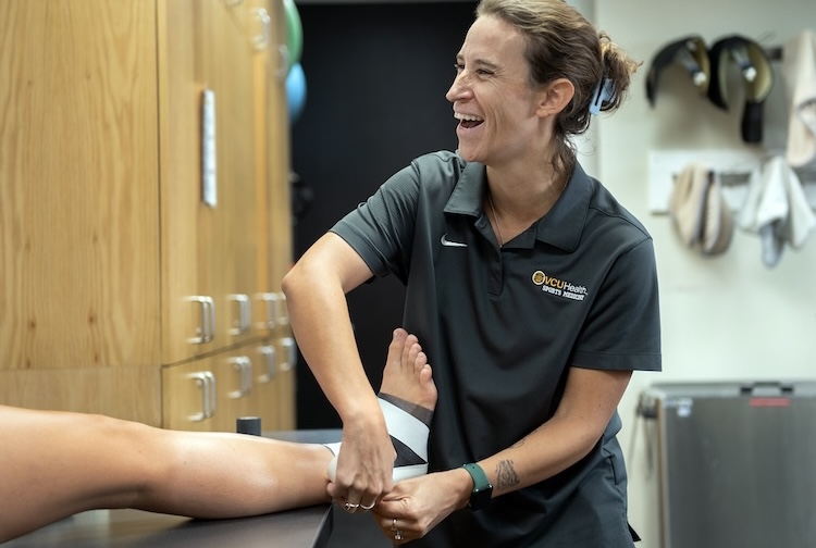 Emily Huss tapes a student's leg in a clinic