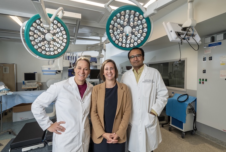 three surgeons stand together in an operating room