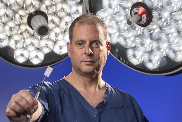 Dr. Isaacs holds up a piece of Nerve Tape with tweezers. Nerve Tape looks like tape.