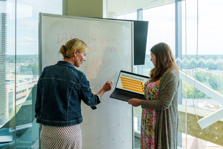 Carolyn Hawley is talking to a research assistant while they write on a white board