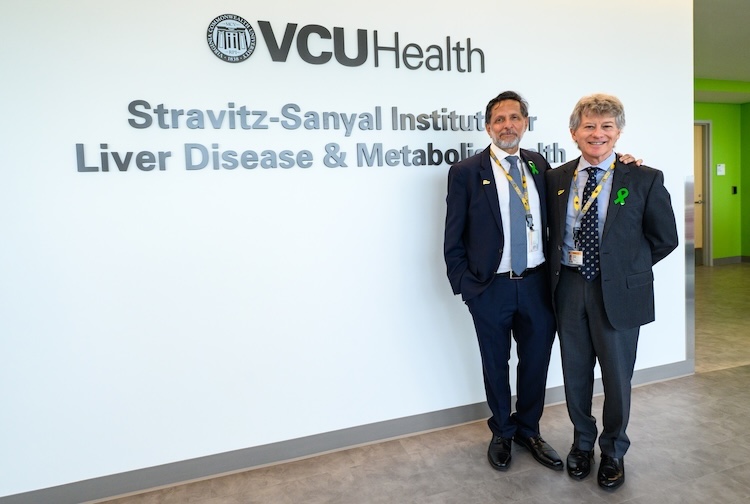 Drs. Sanyal and Stravitz stand in front of a sign for the liver institute, located on the new unit opening at the Adult Outpatient Pavilion.