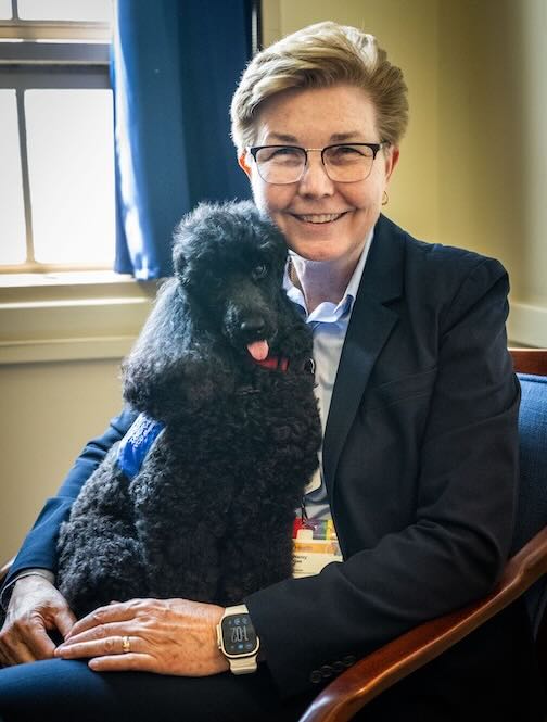 Dr. Gee holding Allie, a black poodle in her lap.