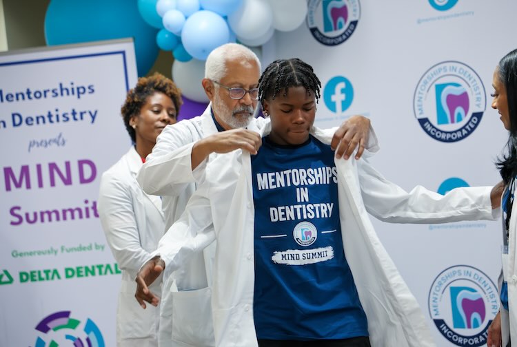 Doctors helping to put on a white coat on high school student.