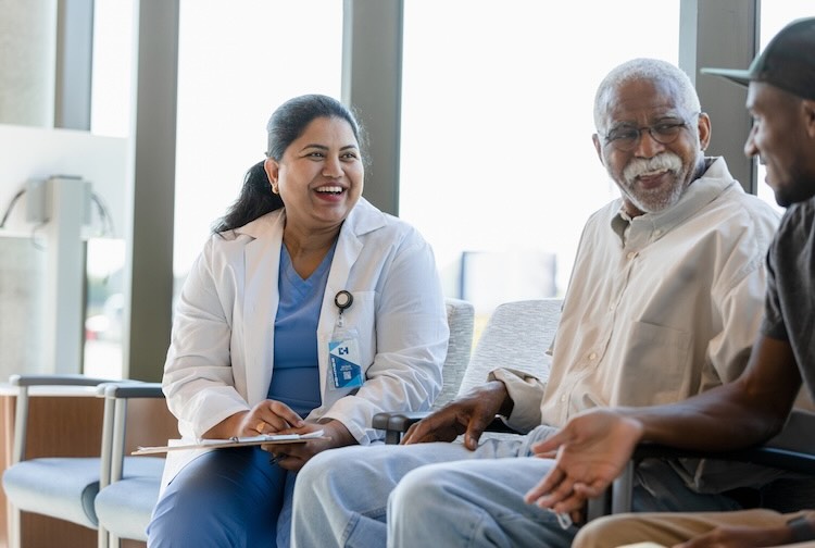 Senior man and young adult son enjoy talking with doctor