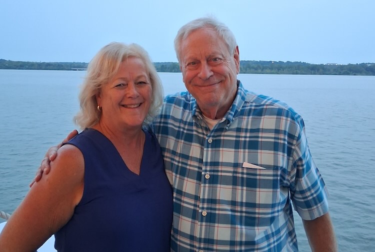 Prostate cancer survivor Alan and his wife smile with their arms around each other beside Lake Gaston in Virginia.