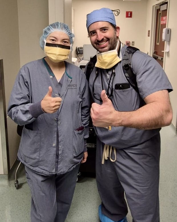 man and woman in scrubs smile with a thumbs up
