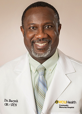 Dr. Baryeh wears a medical white coat and tie with blue and green stripes.