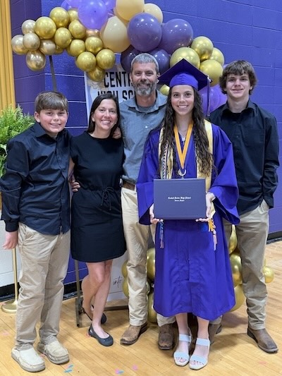 Mackenzie wears a cap and gown and celebrates her graduation with her mom, dad and brothers.