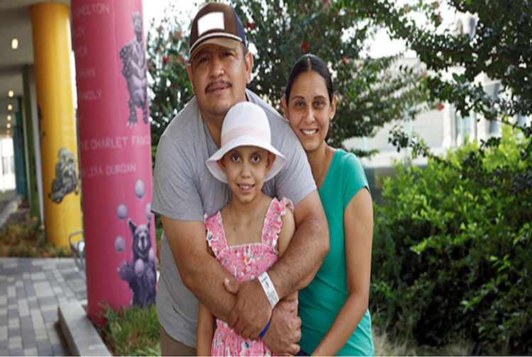 Estella is hugged by mother and father.