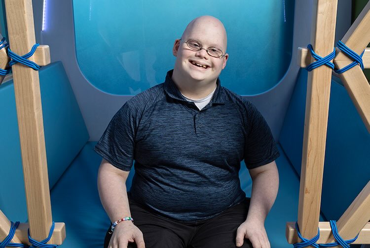 Riley sitting down in blue play area space