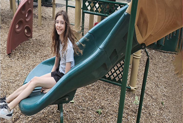 Girl sliding down a slide at a park.