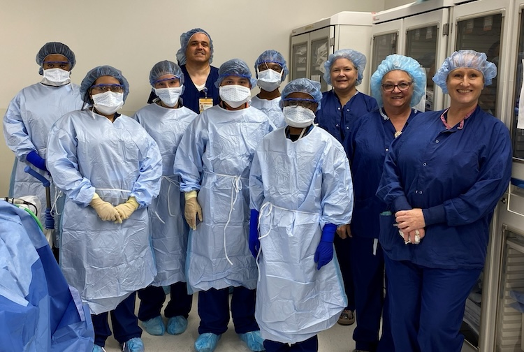 Middle school campers dress in blue medical gowns with hospital workers