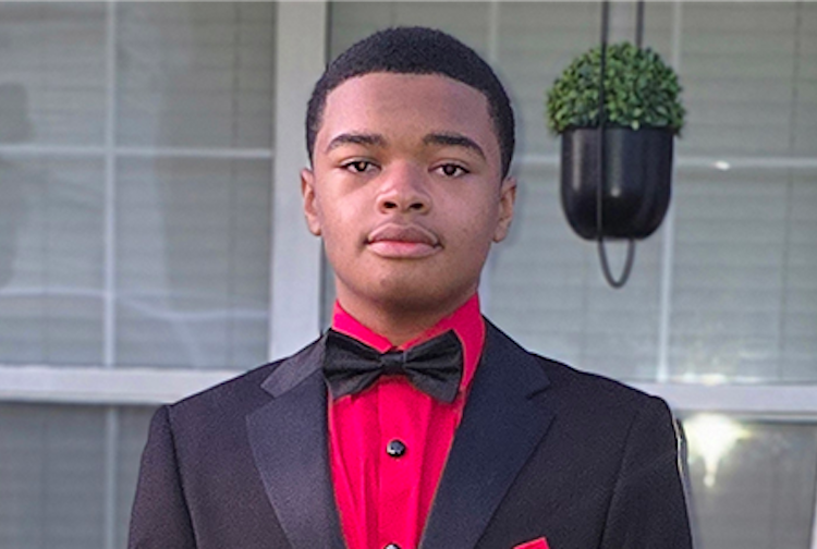 Cameron in a black and red suit and tie.