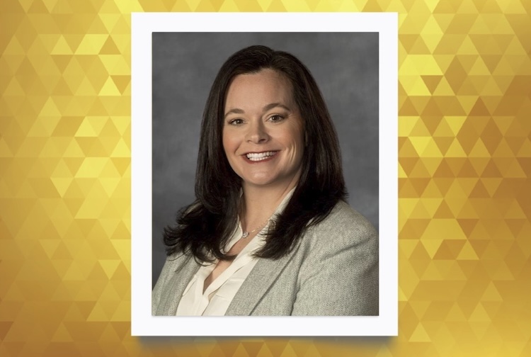 Carissa smiles in a grey suit