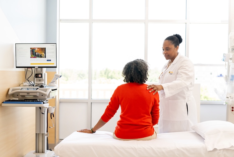 Compassionate female doctor consoles older female patient in a hospital room.