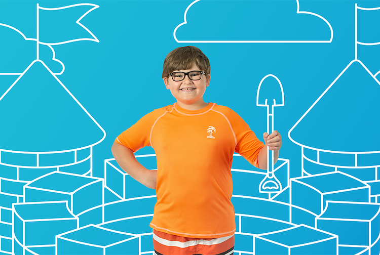 Young boy smiles while wearing a swimsuit and sun shirt. Behind him is a graphic of sand castles and a shovel.