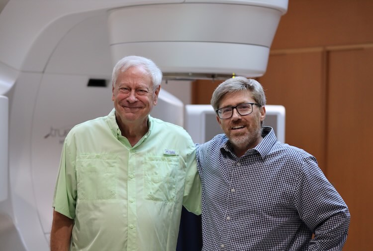 A prostate cancer survivor stands next to his physician in front of a radiation therapy machine at located in South Hill, Va.