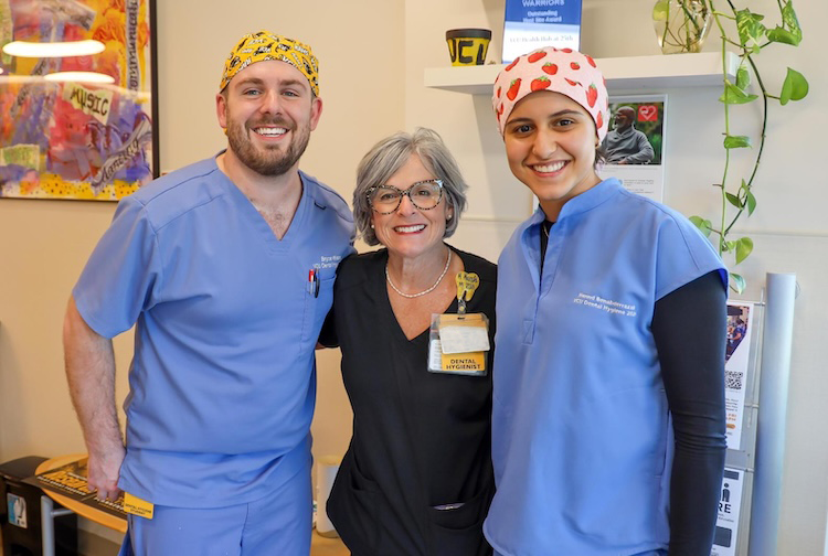 Two students in scrubs with their professor