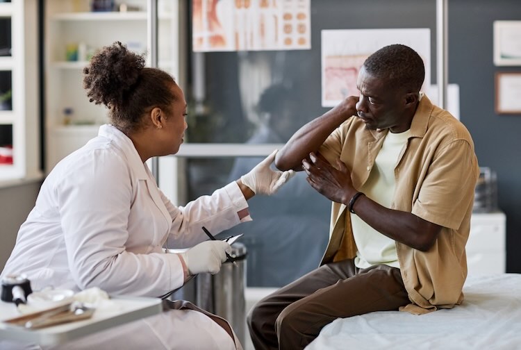 Female dermatologist consulting patient in clinic and examining skin