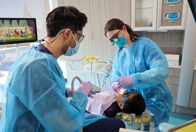 Dr. Carroll examines a child’s mouth along with a dental hygienist.