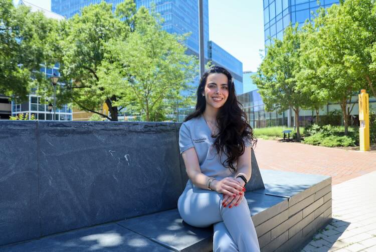 Dr. Khraibut in scrubs sitting on a bench outside