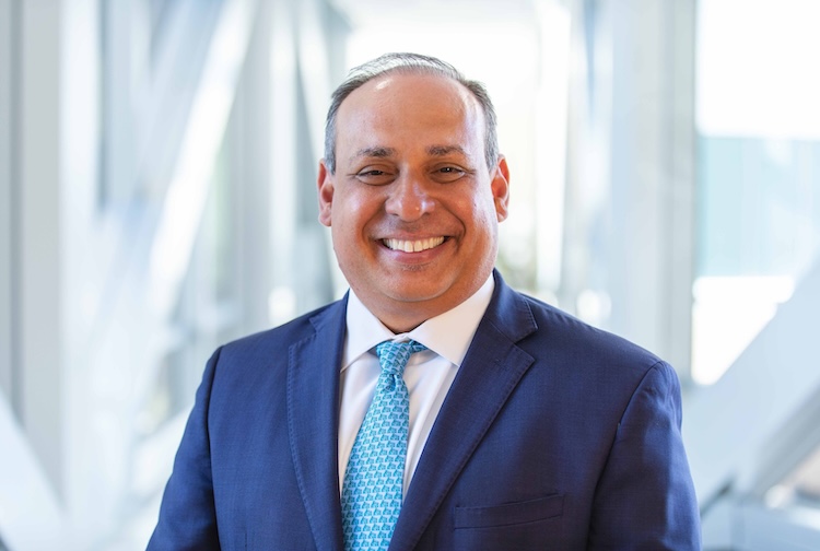 Dr. Saavedra shares a smile in a blue suit.