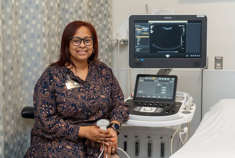 Dr. Demars sitting next to a ultrasound machine